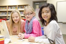 Three student girls reading on an iPad