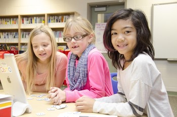 Three student girls reading on an iPad